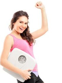 A young happy female holding a weigh scale