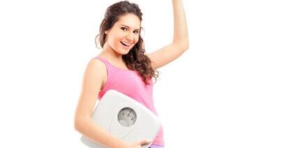 A young happy female holding a weigh scale