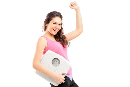 A young happy female holding a weigh scale