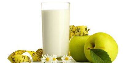 Glass of kefir, green apples and measuring tape isolated
