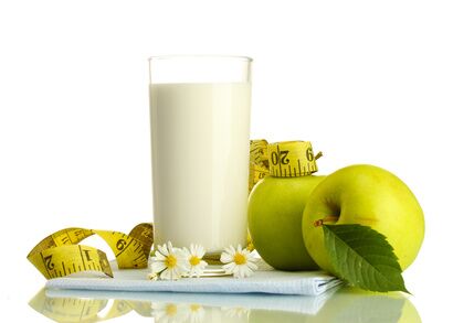 Glass of kefir, green apples and measuring tape isolated