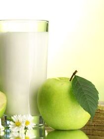 Glass of kefir, apples and crispbreads, on green background
