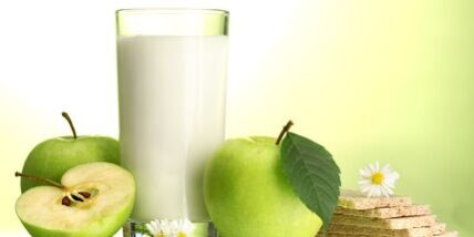 Glass of kefir, apples and crispbreads, on green background